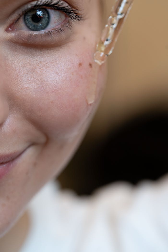 services-03 Close-up image of a person applying skincare serum using a dropper.